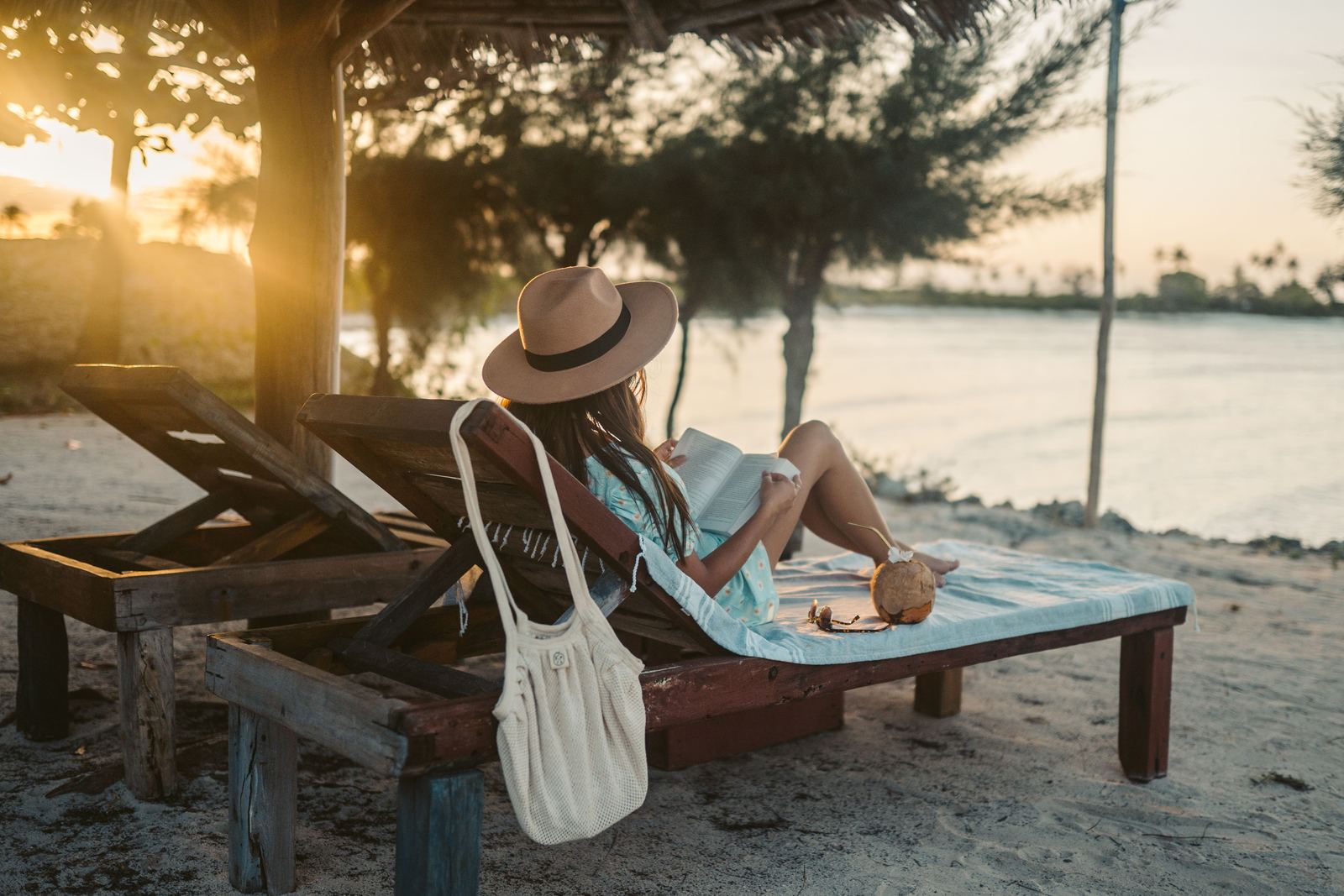 Woman reading on a beach lounger at sunset in Zanzibar